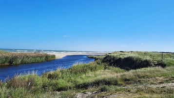 En flod der snor sig gennem et græsklædt landskab under en klar himmel.