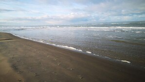 A beach with footprints in the sand and waves approaching the shore. - 6 Person Holiday Home in Bindslev (Bindslev)
