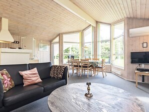 A cozy living room with a black sofa, a round marble coffee table, and a dining area with wooden chairs and a table. - 6 Person Holiday Home in Bindslev (Bindslev)