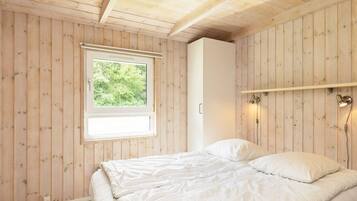 Ein Schlafzimmer mit einem Bett, einem Fenster, einem Kleiderschrank und einer Wandleuchte.