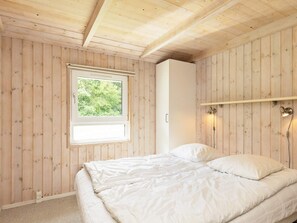 A bedroom with a bed, a window, a wardrobe, and a wall-mounted light fixture. - 6 Person Holiday Home in Bindslev (Bindslev)