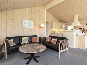 Un salon chaleureux avec un canapé en cuir noir, une table basse en marbre et un plafond en bois.