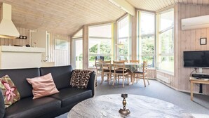 A cozy room with a black leather sofa, a round marble coffee table, and a dining area with wooden chairs and a table. - 6 Person Holiday Home in Bindslev (Bindslev)