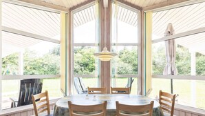 A dining area with a round table, six wooden chairs, and a hanging light fixture. - 6 Person Holiday Home in Bindslev (Bindslev)