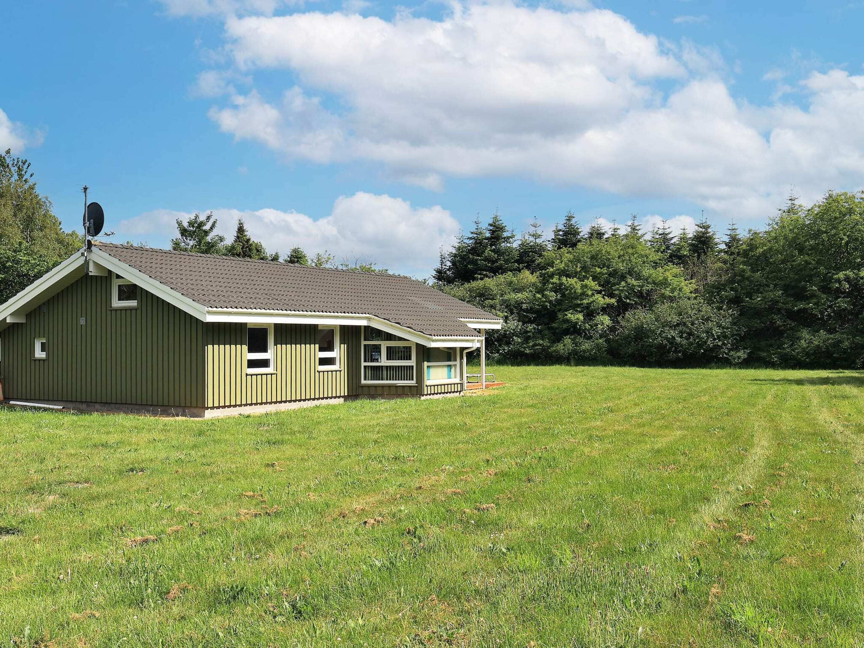 A single-story building with a sloped roof, a small porch, and a satellite dish on the roof.
