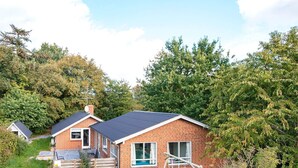 A two-story brick house with a dark roof, a swing set, and a small garden area. - 4 Star Holiday Home in Glesborg (Glesborg)