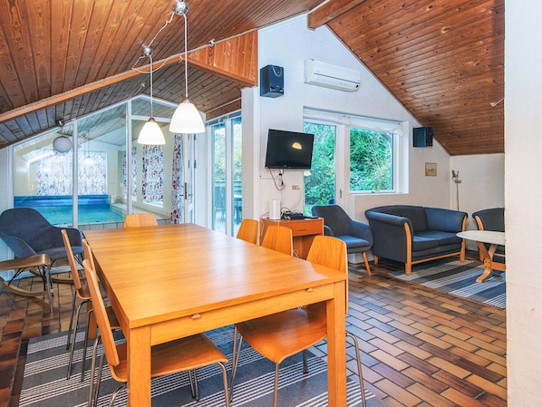 A spacious room with a wooden dining table, chairs, and a television.