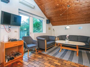 A cozy living room with a wooden ceiling, a flat-screen TV, grey sofas, a wooden coffee table, and a TV stand with electronic devices. - 4 Star Holiday Home in Glesborg (Glesborg)