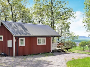 A red building with a metal roof, a white door, and a small porch with a bench.