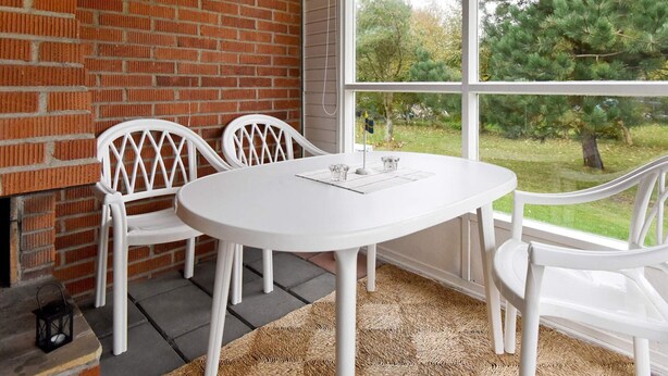 A room with a brick wall, a white table, and two white chairs. - 5 Person Holiday Home in Glommen (Glommen)