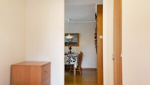 A room with two beds, a wooden dresser, a dining table with a patterned tablecloth, and a painting on the wall. - 5 Person Holiday Home in Glommen (Glommen)