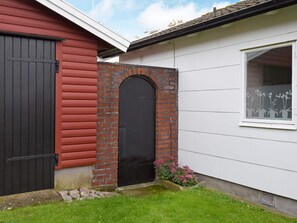 A red and white building with a black door, a brick archway, and a window with a plant decoration.