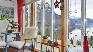 Une pièce chaleureuse avec une grande fenêtre, des meubles en bois et des objets décoratifs.