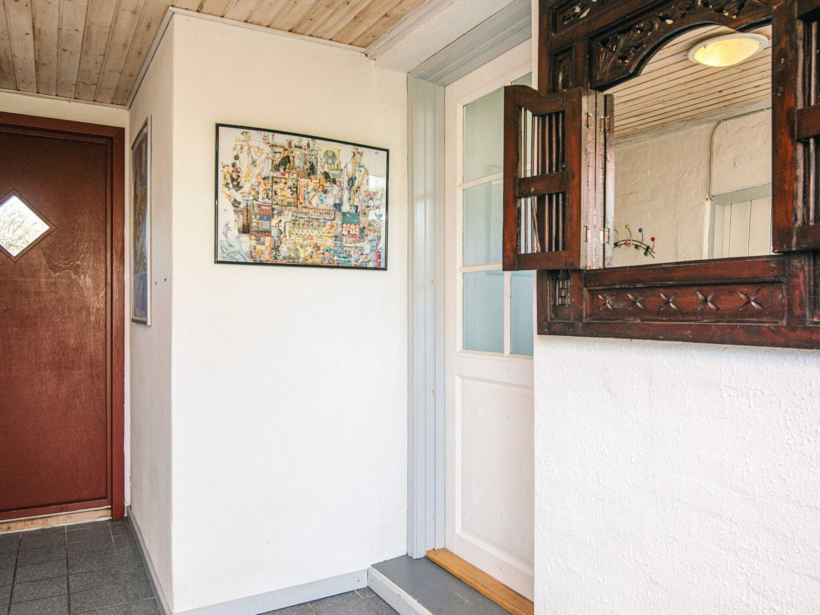 A hallway with a wooden door, a framed artwork, and a mirror with a decorative frame.