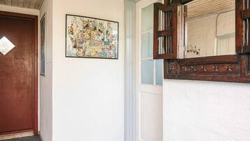 A hallway with a wooden door, a framed artwork, and a mirror with a decorative frame.