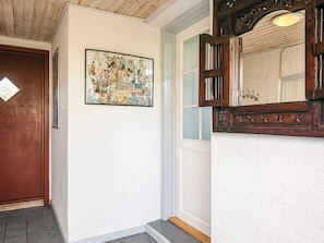 A hallway with a wooden door, a framed artwork, and a mirror with a decorative frame. - 8 Person Holiday Home in Bindslev-by Traum (Bindslev)