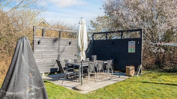 Eine Terrasse mit Tisch und Stühlen, ein überdachter Sitzbereich und ein Holzzaun.