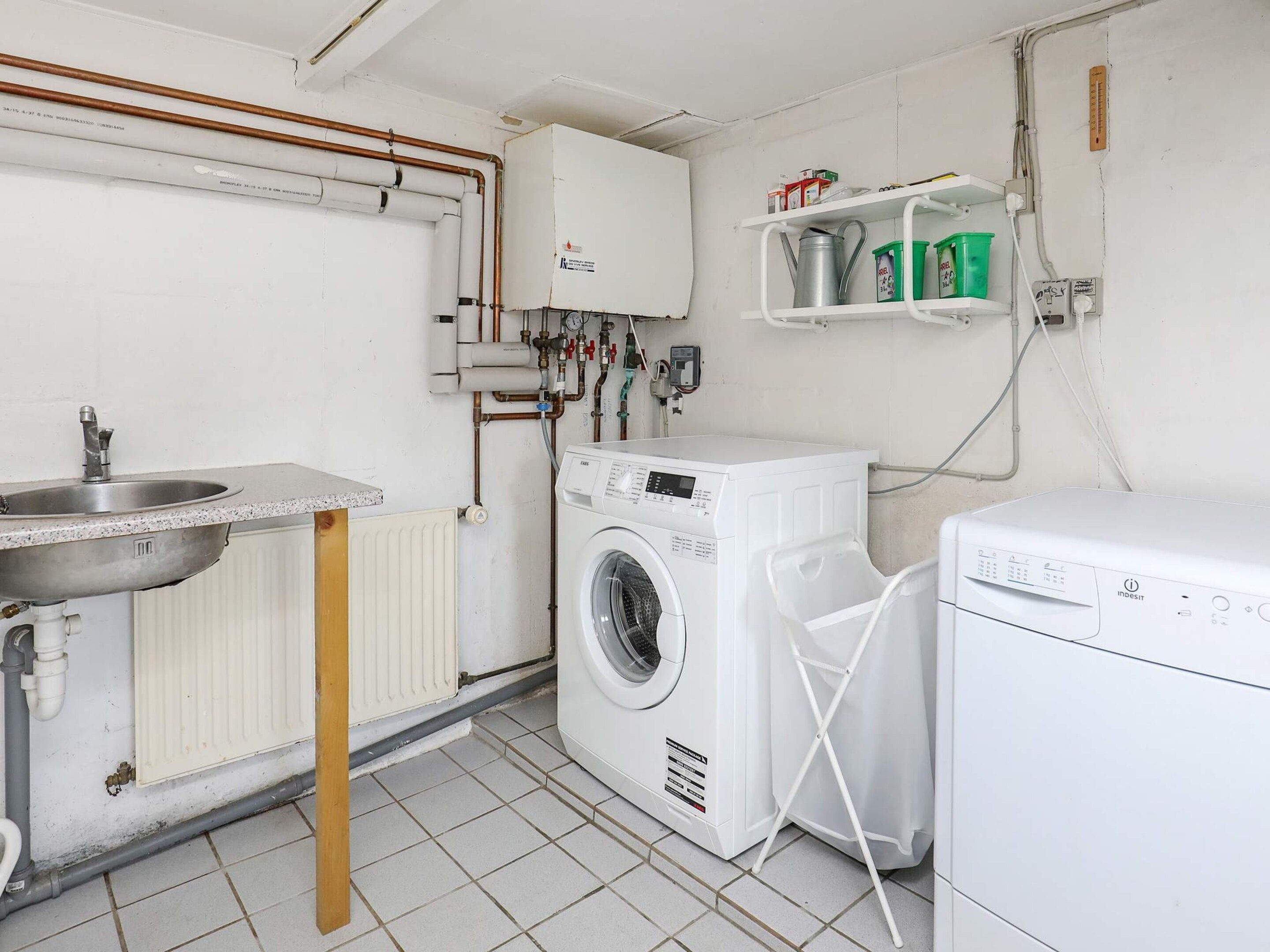 A laundry room with a washing machine, a dryer, a sink, and a radiator.