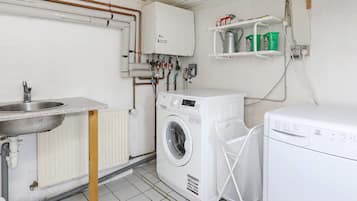 A laundry room with a washing machine, a dryer, a sink, and a radiator.