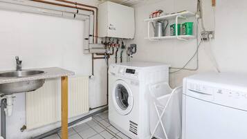 A laundry room with a washing machine, a dryer, a sink, and a radiator.