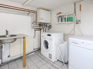 A laundry room with a washing machine, a dryer, a sink, and a radiator. - 8 Person Holiday Home in Bindslev-by Traum (Bindslev)