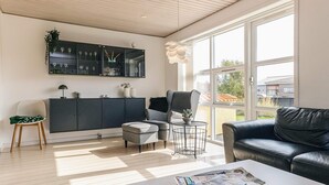 A modern living room with a sofa, armchair, and a coffee table with magazines.