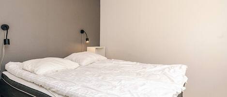 Une chambre à coucher moderne avec un lit, deux lampes de chevet et une table de chevet.