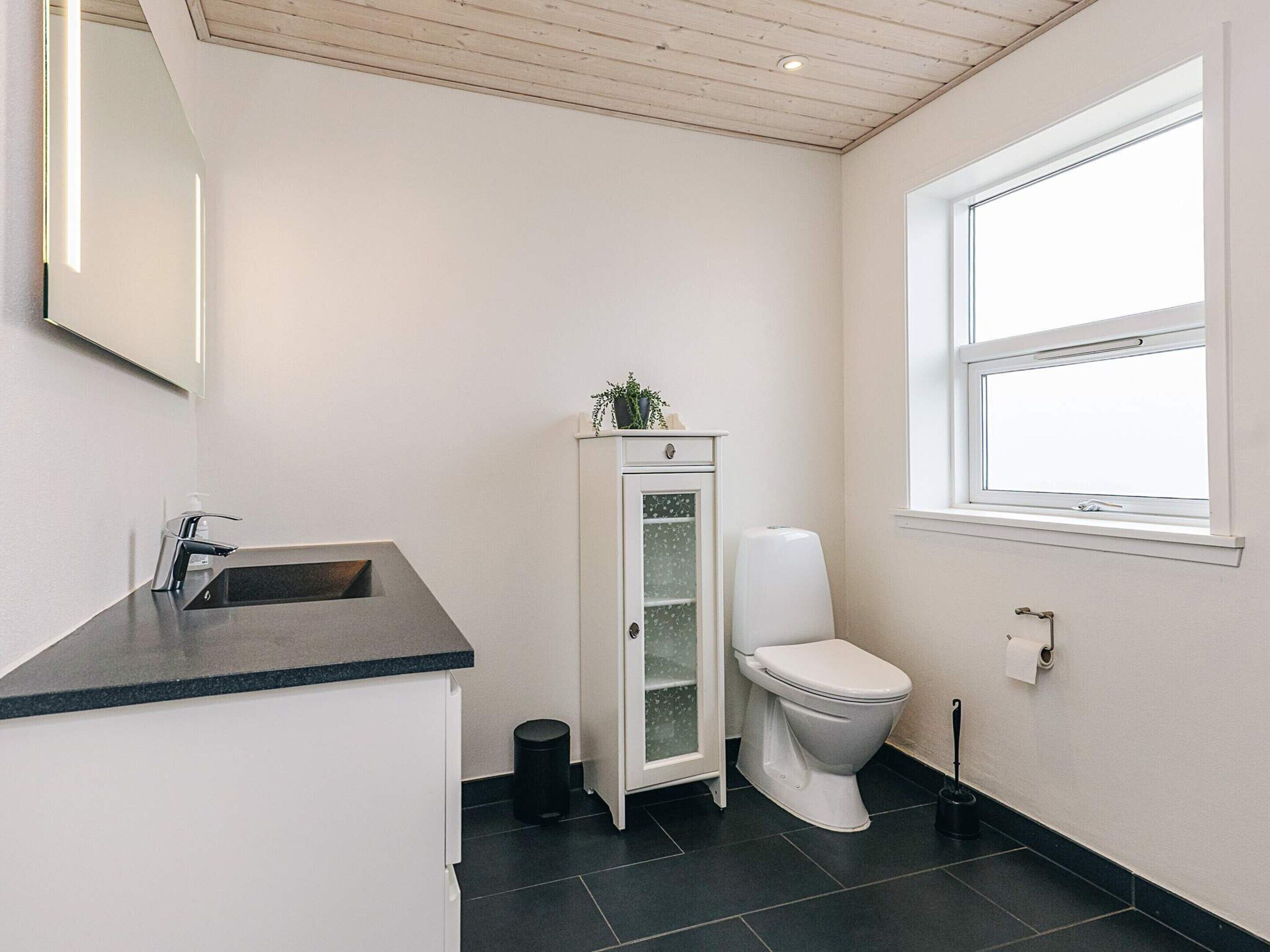 Ein Badezimmer mit Waschbecken, Toilette und Fenster.