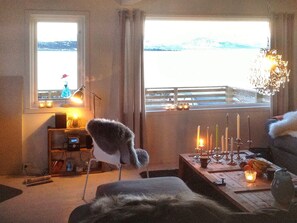 A cozy living room with a view of a snowy landscape, a fireplace, and a chandelier. - 6 Person Holiday Home in Nord-lenangen (Lyngen)