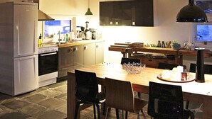 Una cocina moderna con comedor, que cuenta con una isla grande, un refrigerador, un horno y un televisor montado en la pared.