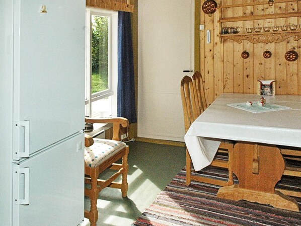 A room with a dining table, chairs, a refrigerator, and a window with curtains. - 3 Person Holiday Home in Frei (Kristiansund)