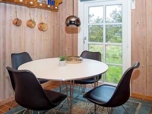 A dining area with a round table, four chairs, a potted plant, and a decorative bowl.