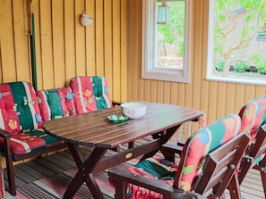 A wooden deck with a table and colorful upholstered chairs. - 5 Person Holiday Home in Mellbystrand (Mellbystrand)