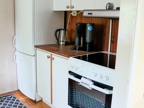 Uma cozinha compacta equipada com fogão, cafeteira e chaleira.