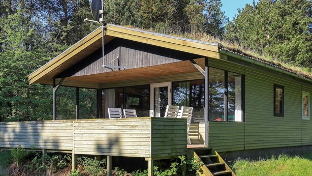A small cabin with a covered porch and a satellite dish.