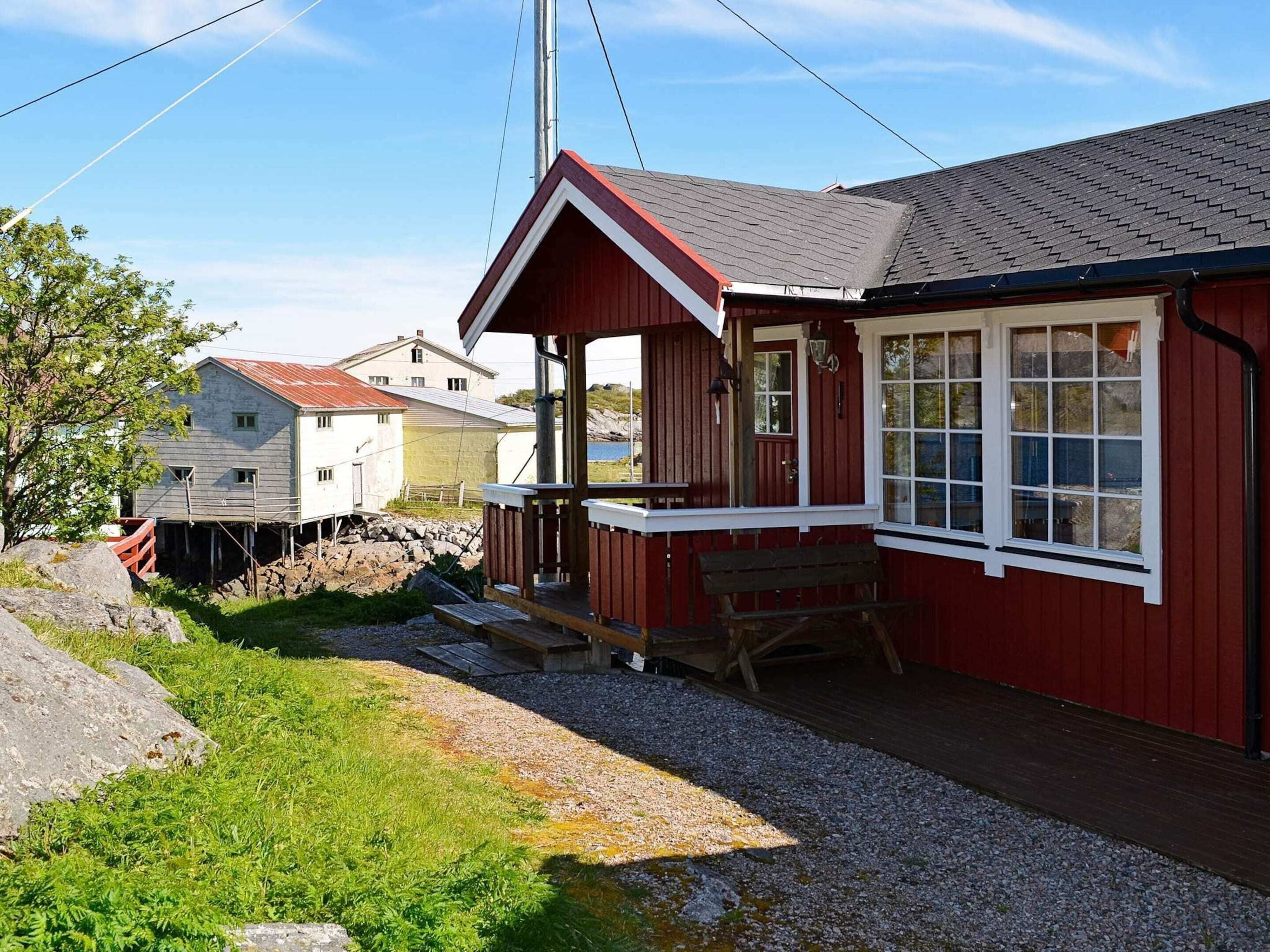 A red wooden building with a porch, a bench, and a small table.