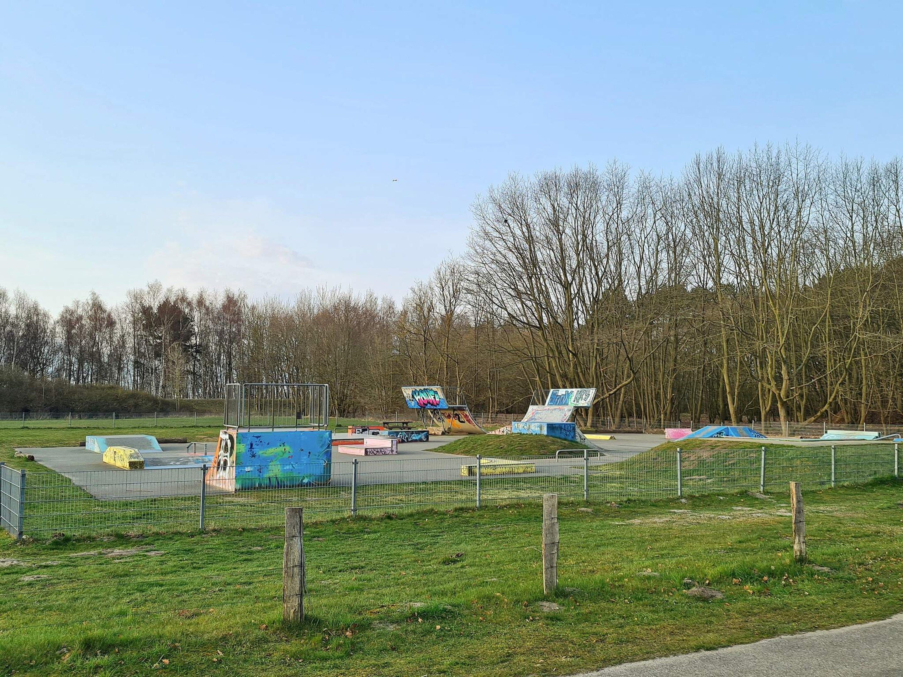 An outdoor skate park with ramps and graffiti-covered structures.