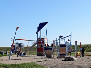 A playground with various play structures including a slide, climbing frames, and swings.