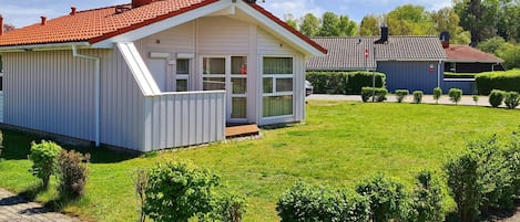 A single-story house with a red-tiled roof, a front porch, and a well-maintained lawn.