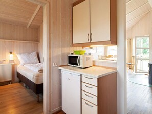 A compact room with a bed, kitchenette, and a view of the outdoors.