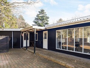 Een zwarte houten hut met een overdekte veranda en een grote schuifpui.