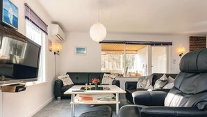 Een woonkamer met een bank, een salontafel, een televisie en een lamp.