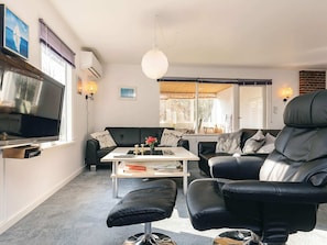 Een woonkamer met een bank, een salontafel, een televisie en een lamp.