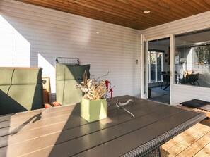 Un espace extérieur abrité, aménagé avec une table, des chaises et un pot de fleurs.