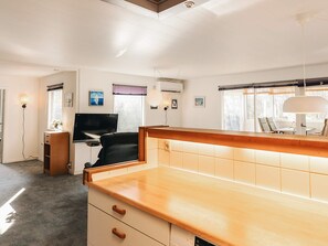 Een moderne keuken met een houten aanrecht, een inbouw vaatwasser, en een eethoek met een tafel en stoelen.