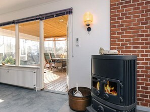 Un espace extérieur accueillant, aménagé avec un poêle à bois, une table, des chaises et un panier.