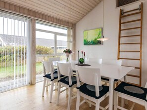 A dining area with a white table and chairs, a painting on the wall, and a wooden ladder.