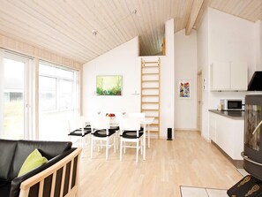 A modern interior with a dining area, kitchen, and a loft space. - Beautiful Holiday Home in Blokhus with Hot Tub (Blokhus)