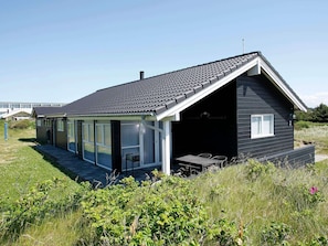 A modern house with a large glass door entrance, a covered patio, and a black exterior. - Beautiful Holiday Home in Blokhus with Hot Tub (Blokhus)