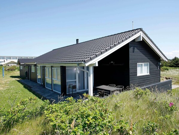 A modern house with a large glass door entrance, a covered patio, and a black exterior.